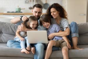 A family seated on a sofa in their living room looking at their laptop reviewing All Risks Cover in Ireland.