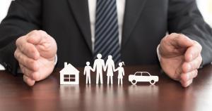 Man in suit with a house, car and family cut outs on desk. Image for excess insurance.