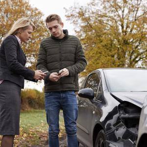 Two drivers exchanging insurance details after a car crash on an Irish road.