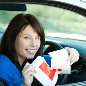 Girl in car after passing a driving test in Ireland with L sign.