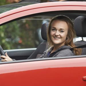 A woman in a red car. Save on Car Insurance in Ireland.
